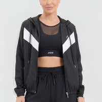 Chaqueta deportiva color negro, con cierre frontal, capucha ajustable y detalles en color blanco.