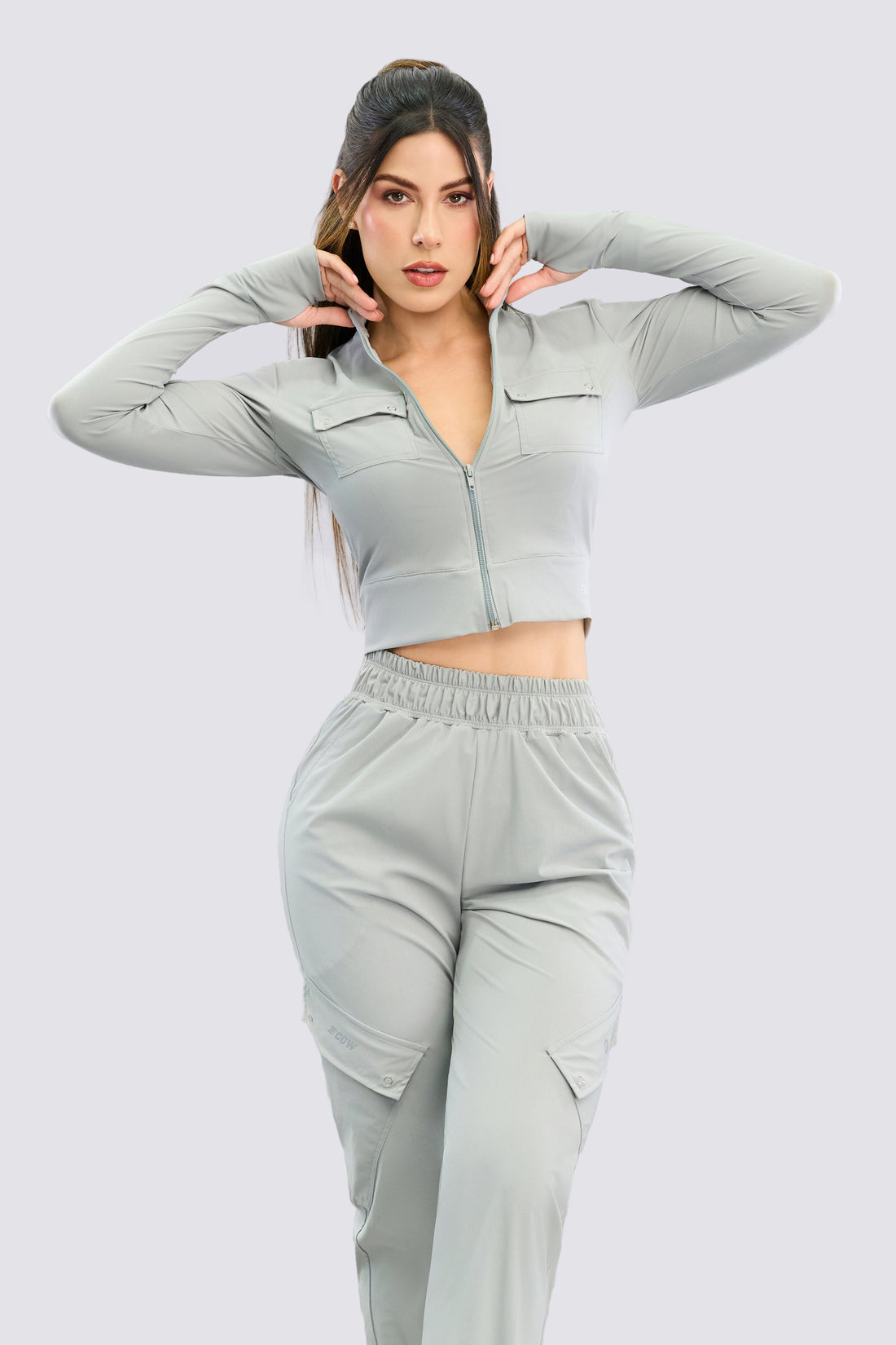 Chaqueta full zip, color gris, con bolsillos al frente y orificio en el pulgar.