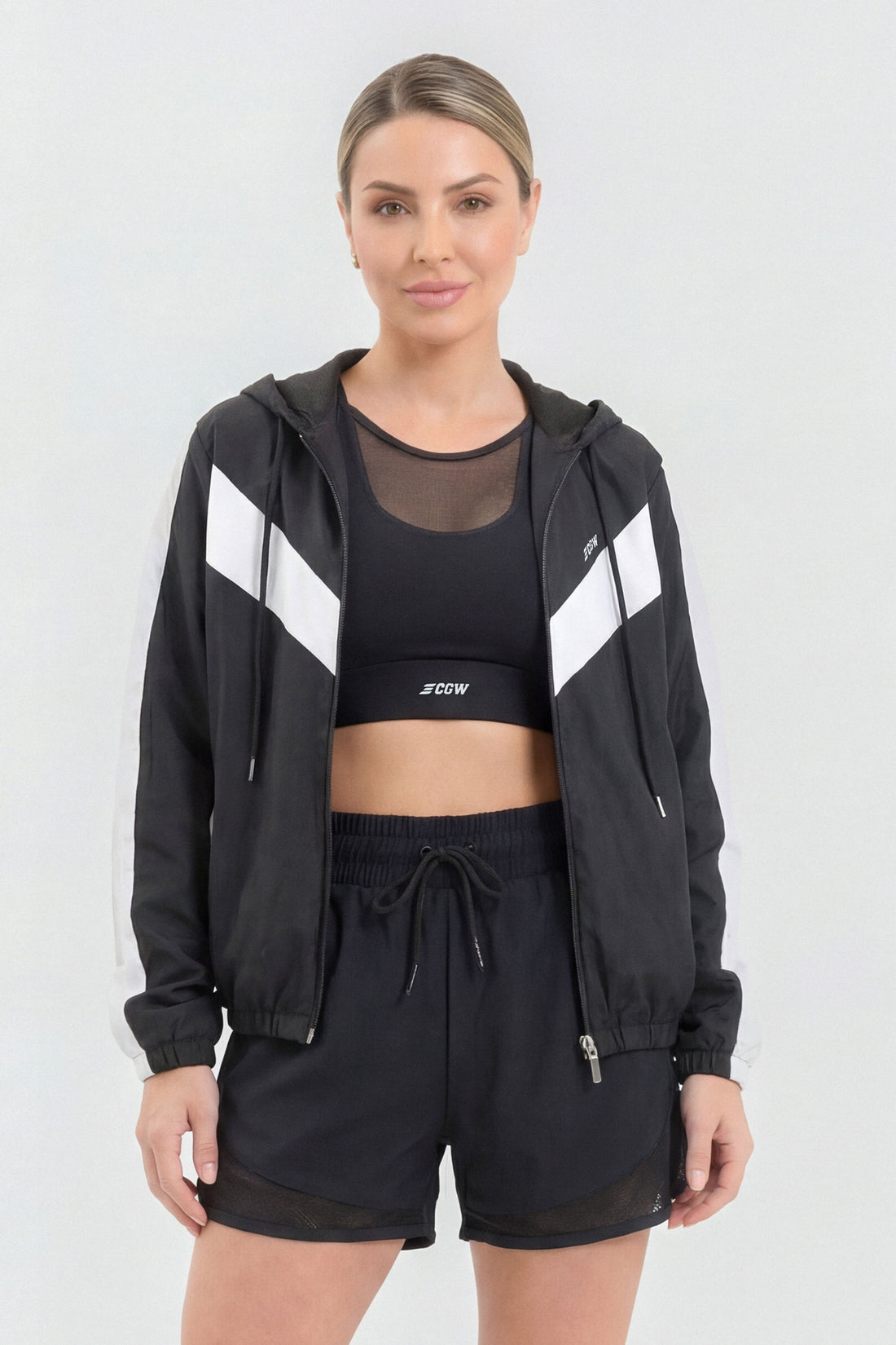 Chaqueta deportiva color negro, con cierre frontal, capucha ajustable y detalles en color blanco. 