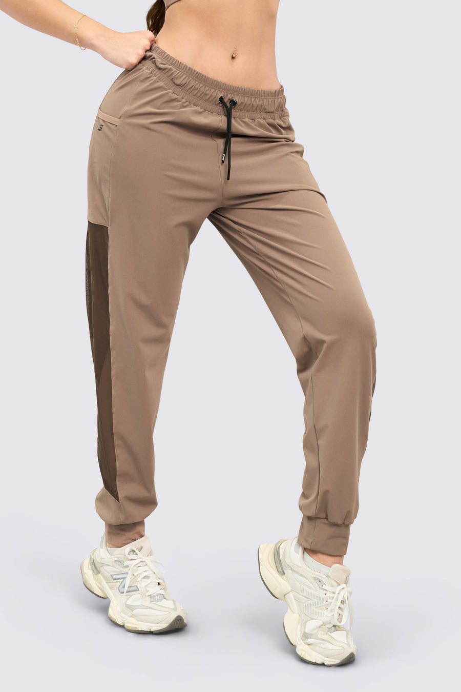 Jogger deportivo color mocca, de tiro alto, pretina ajustable, mallas laterales y bolsillos funcionales. 