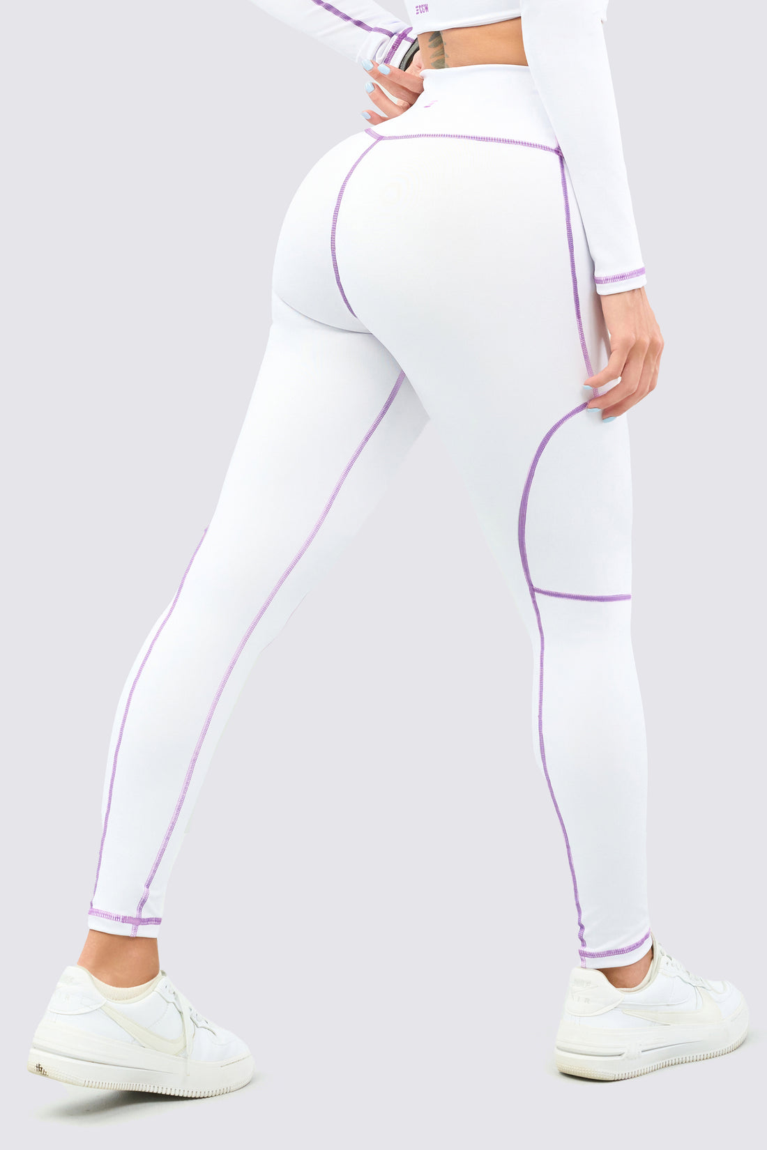 Leggings color blanco, con costuras en color lila, con talle alto.