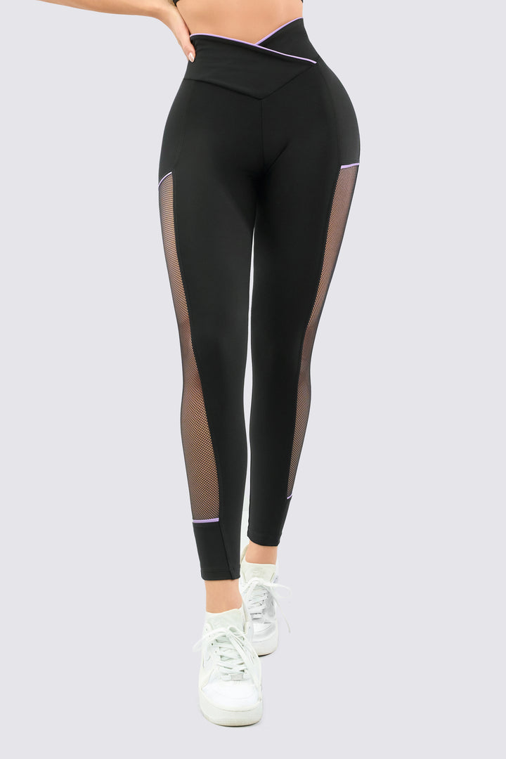 Leggings color negro, con mallas laterales y venas en color lila, con talle cruzado en V.