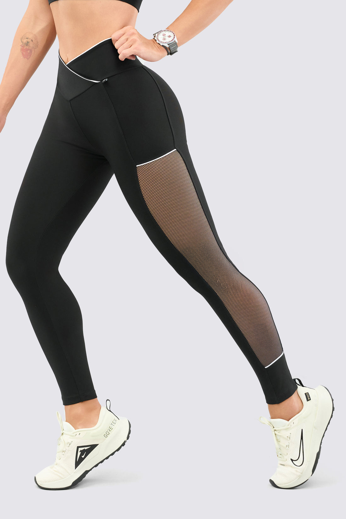 Leggings color negro, con malla, de talle alto cruzado en V.
