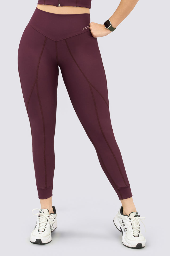 Leggings deportivo color vinotinto, tiro alto, con costuras del mismo tono, que estilizan la figura. 