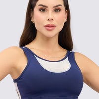 Top gym mujer azul marino con panel malla blanca y soporte firme. Transpirable, cómodo y diseño bicolor exclusivo.
