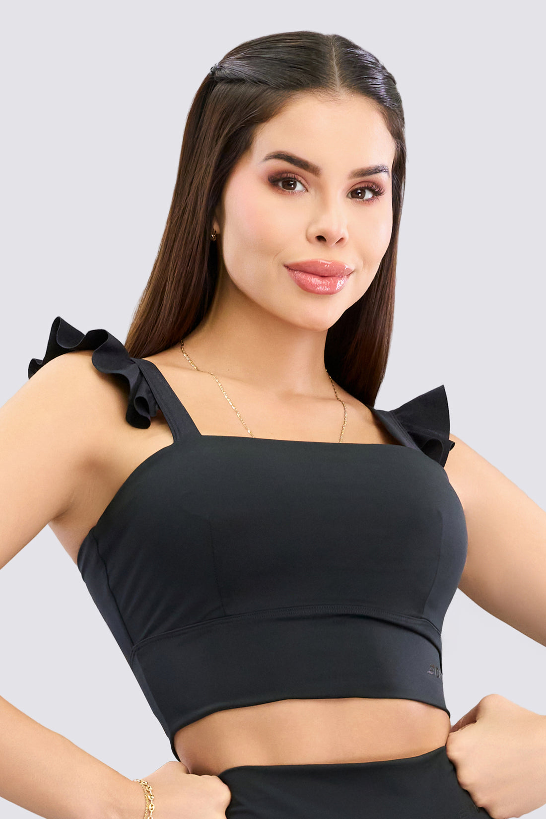 Top deportivo color negro, con tirantes de volantes, escote cuadrado y soporte medio. 